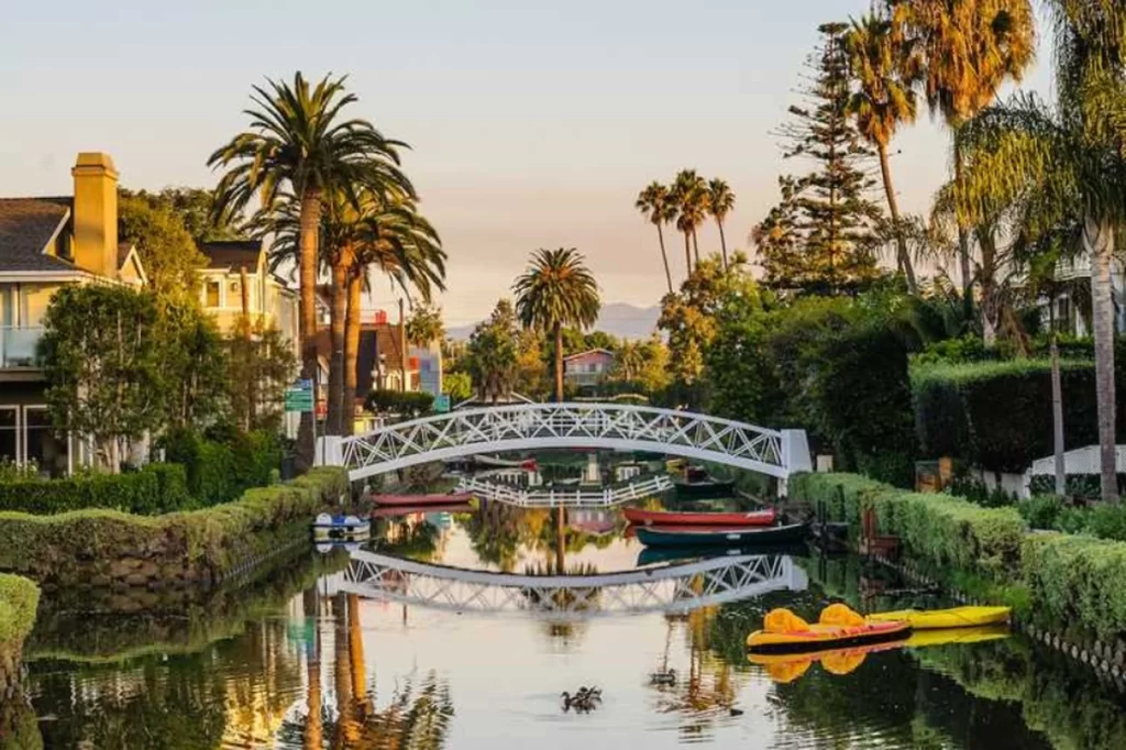 Vista dos famosos canais residenciais de Venice, com ponte e barcos coloridos.