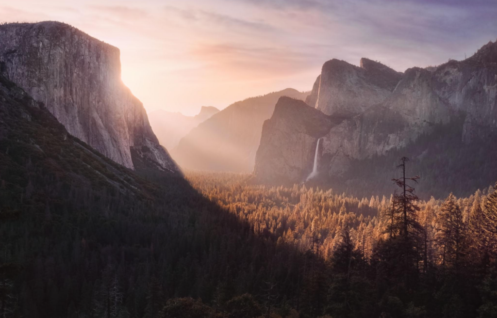 Paisagem suave do vale de Yosemite com luz dourada da manhã incidindo sobre montanhas e floresta.