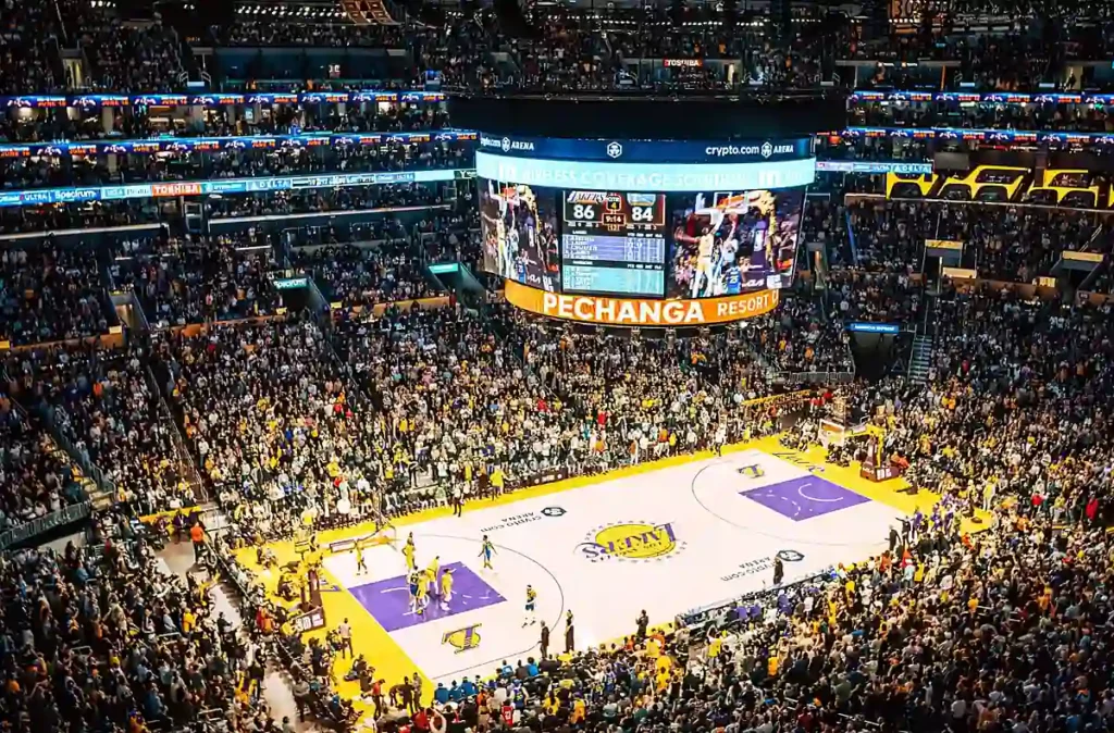 Experiência de assistir a um jogo do Los Angeles Lakers na Crypto.com Arena, em Los Angeles. A fotografia mostra a quadra da NBA vista das arquibancadas, o telão central e milhares de torcedores acompanhando a partida.